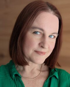 headshot of Sumara Meers with auburn bobbed hair, a green collared short, a small smile at the camera.